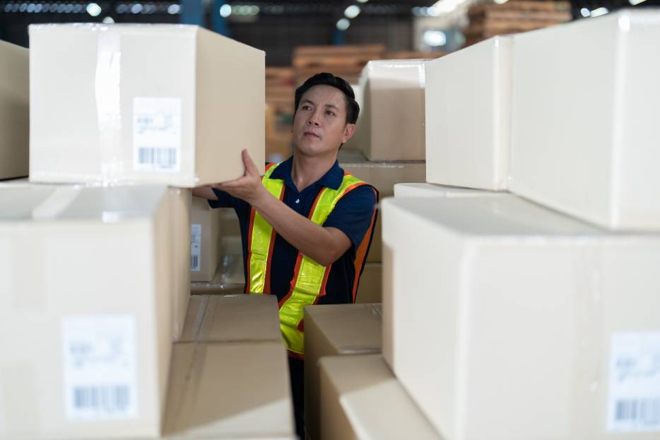 Empleado de almacén apila una caja de cartón 