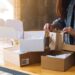 emprendedora arregla sus productos en cajas de cartón