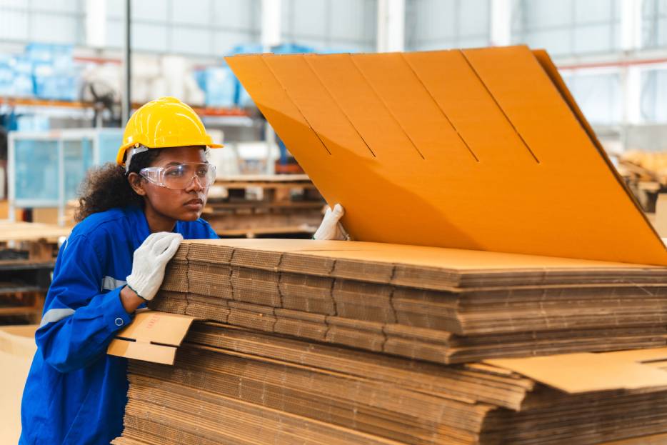 Trabajadora selecciona el tipo de material adecuado para una caja de cartón resistente